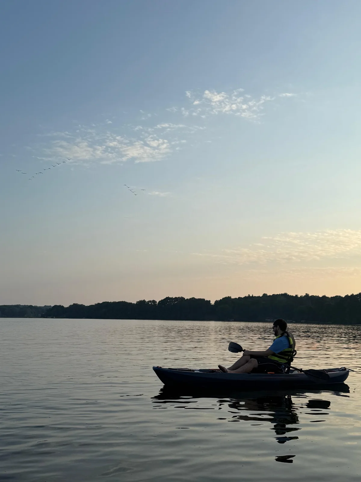 A kayaker on calm water under an evening sky